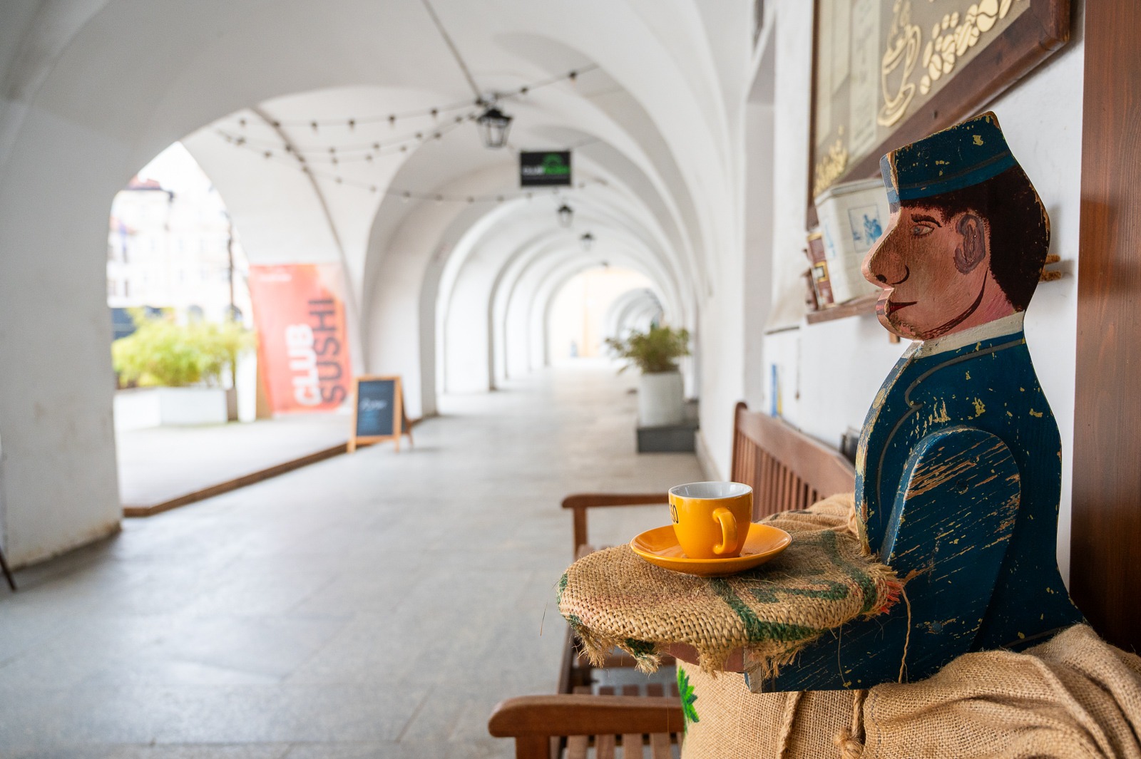 Dřevěná socha číšníka s šálkem espressa pod arkádami Radničního náměstí v Jelení Hoře