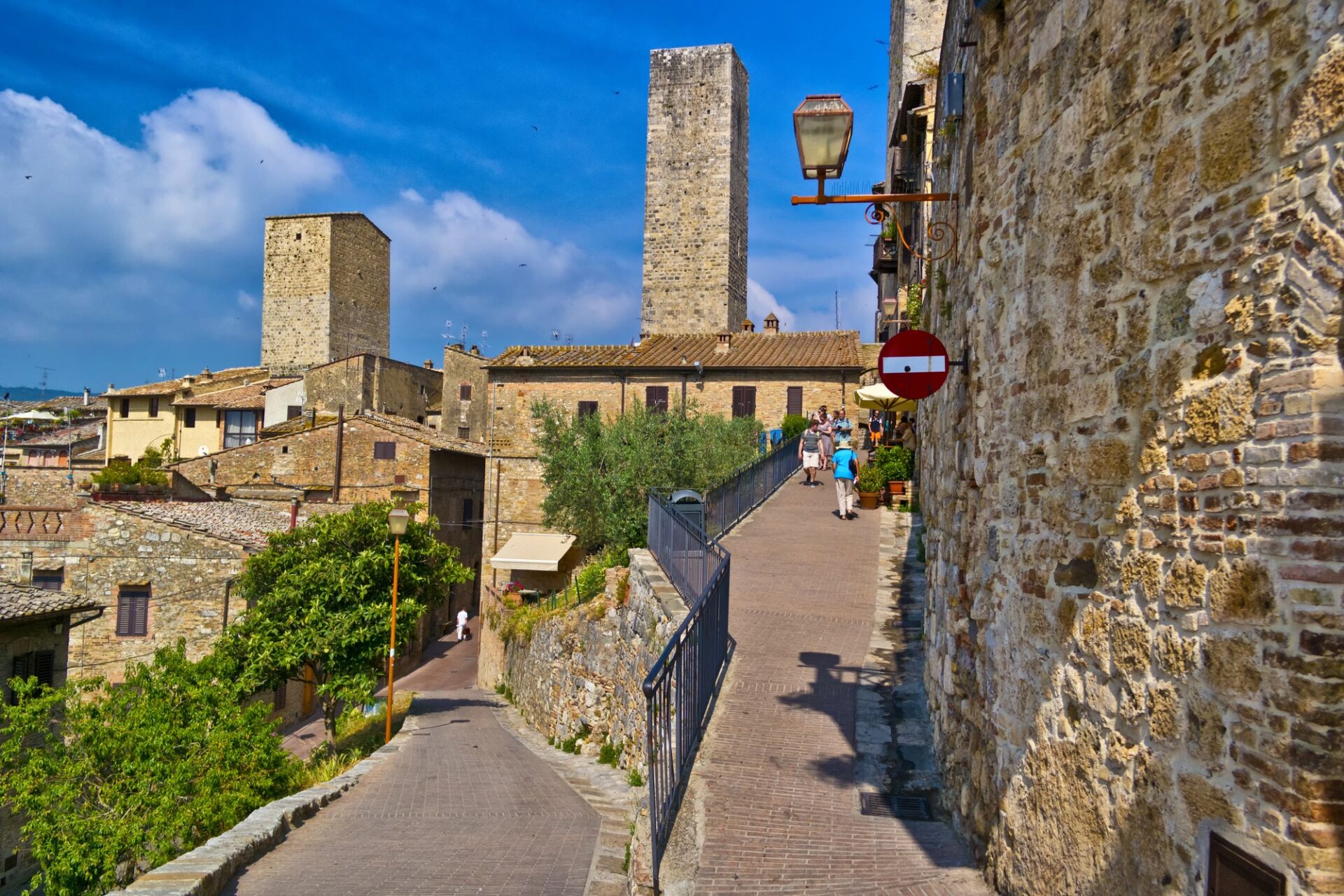 Ulice historického centra San Gimignana s turisty a středověkými věžemi
