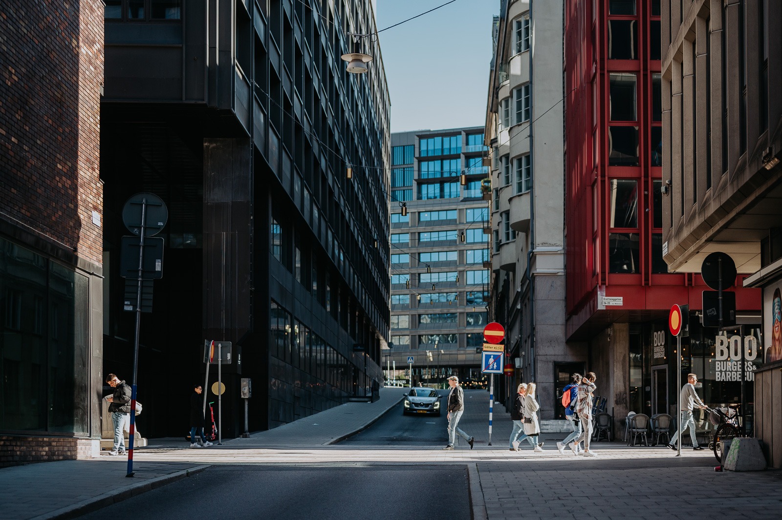 Moderní centrum Stockholmu s chodci na přechodu mezi prosklenými budovami