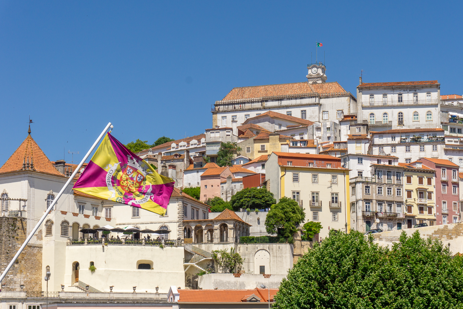 Panorama starého města Coimbra na kopci s portugalskou královskou vlajkou v popředí