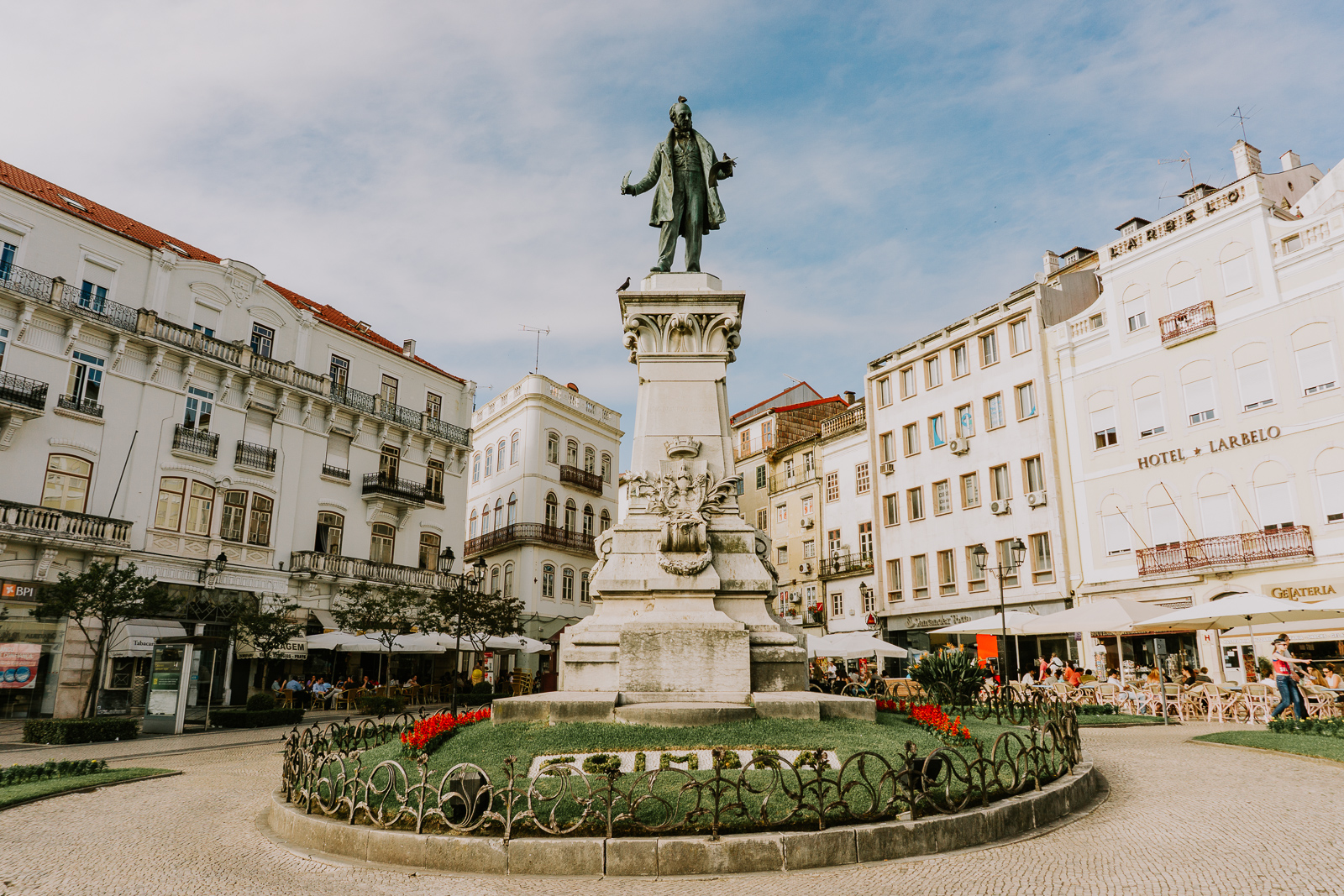 Náměstí Largo da Portagem v Coimbře se sochou a kavárnami