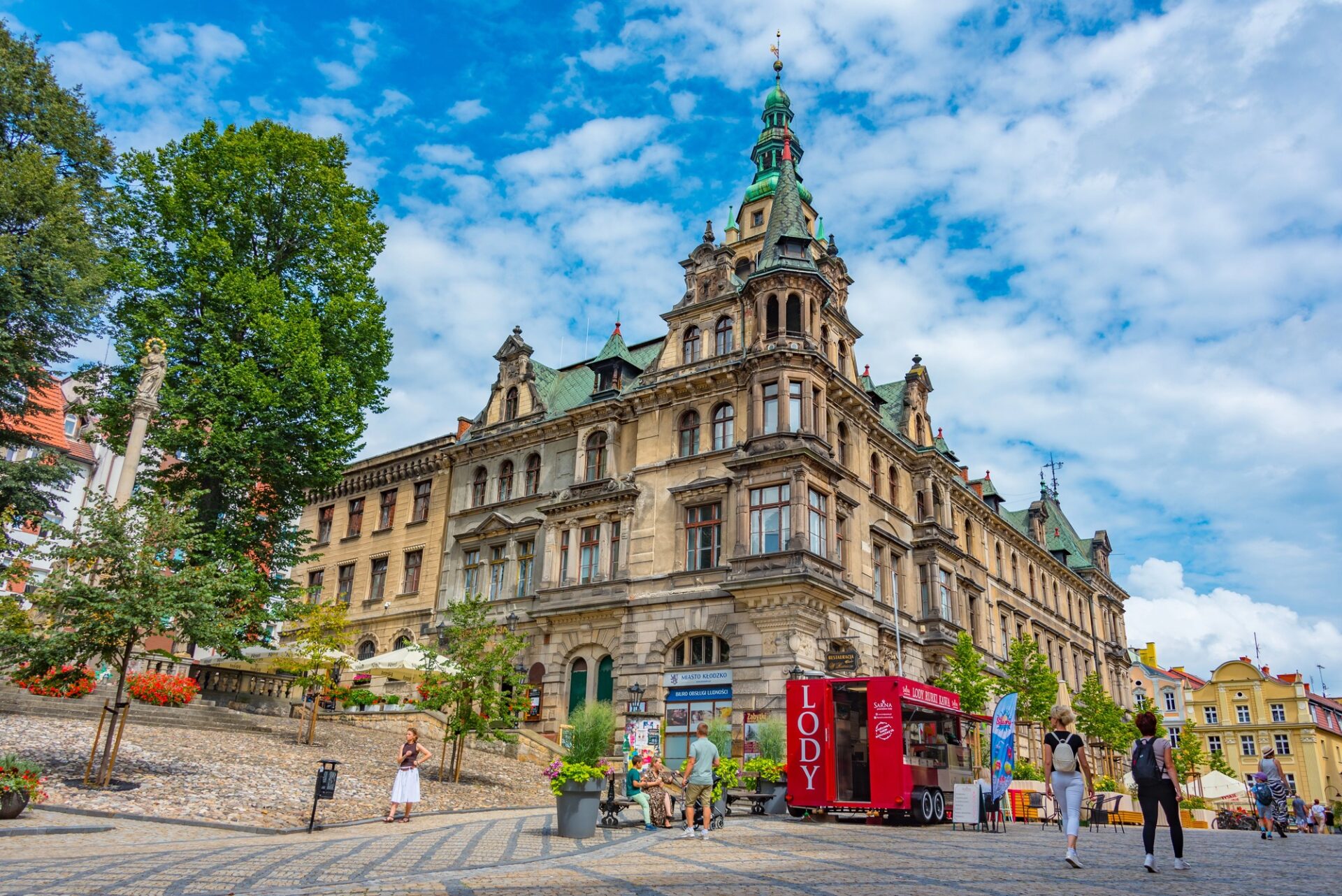 Slunečný rynek v Kladsku s radnicí a stánkem se zmrzlinou