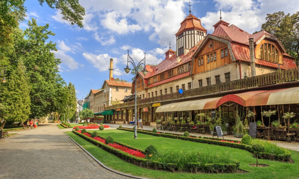 Promenáda s historickou dřevěnou budovou a obchůdky v Parku Zdrojowym v Kudowě-Zdroji