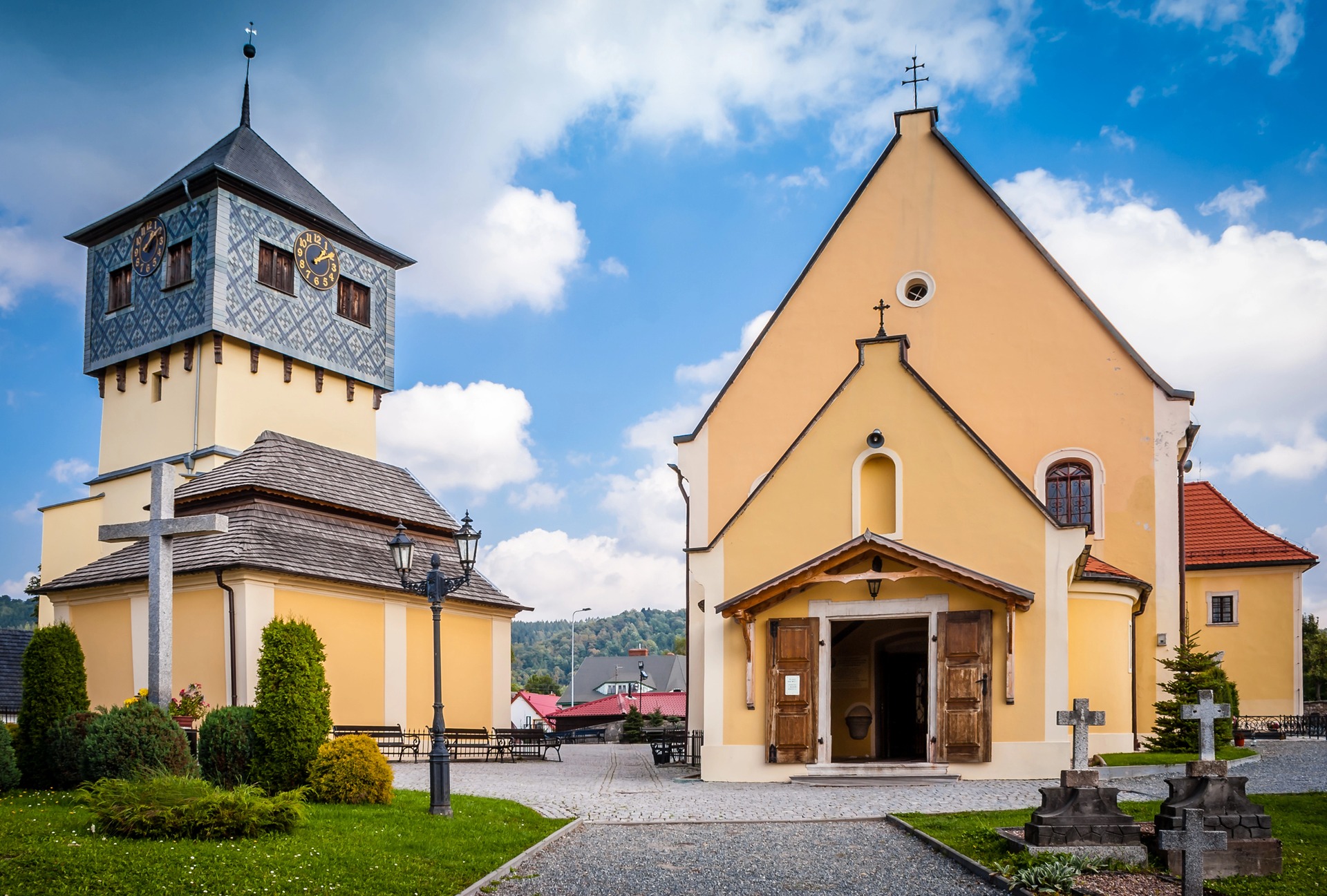 Venkovský kostel s dřevěnou zvonicí a hřbitovními kříži v Czermné