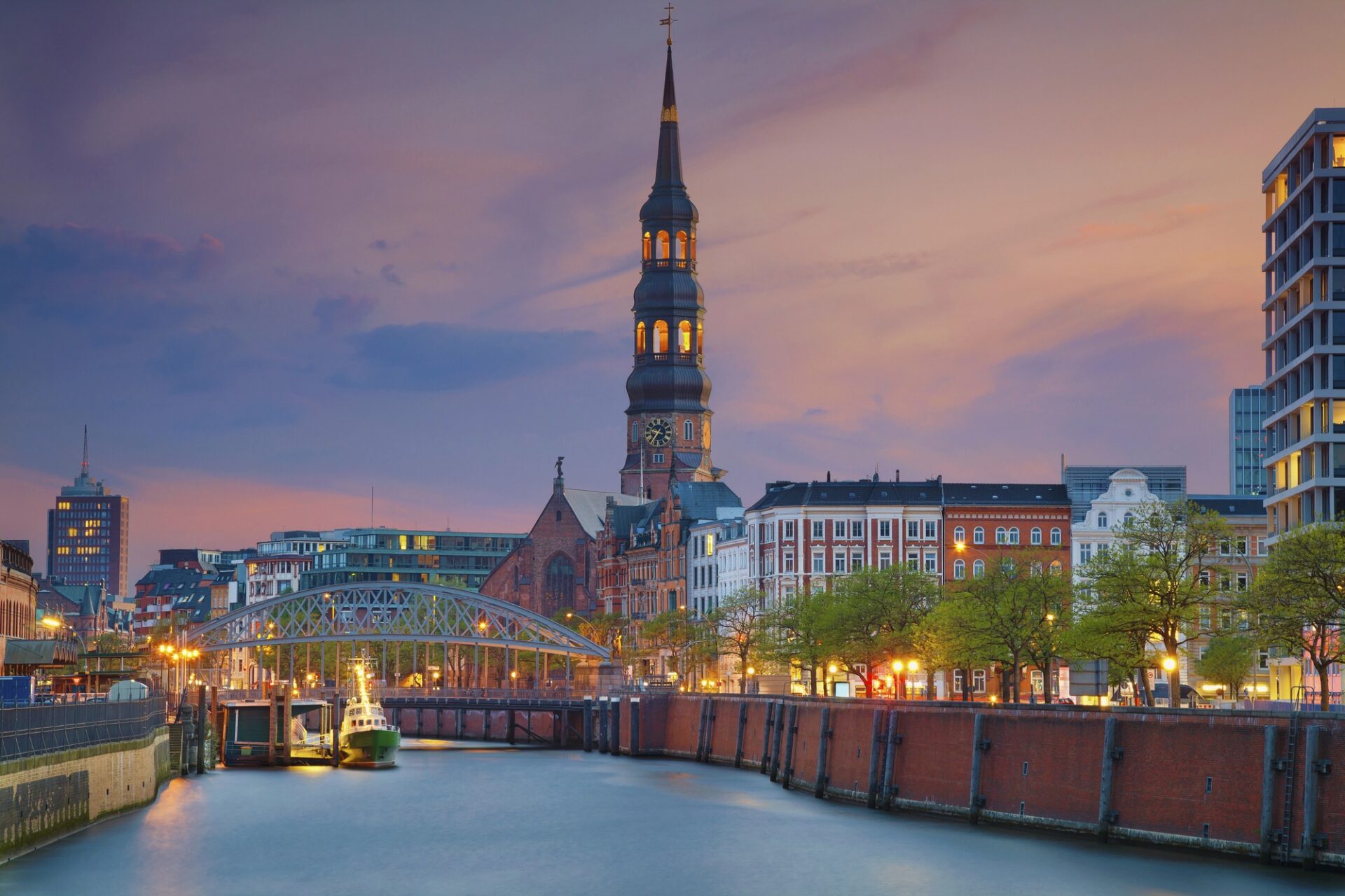 Večerní panorama centra Hamburku s kanálem a kostelní věží