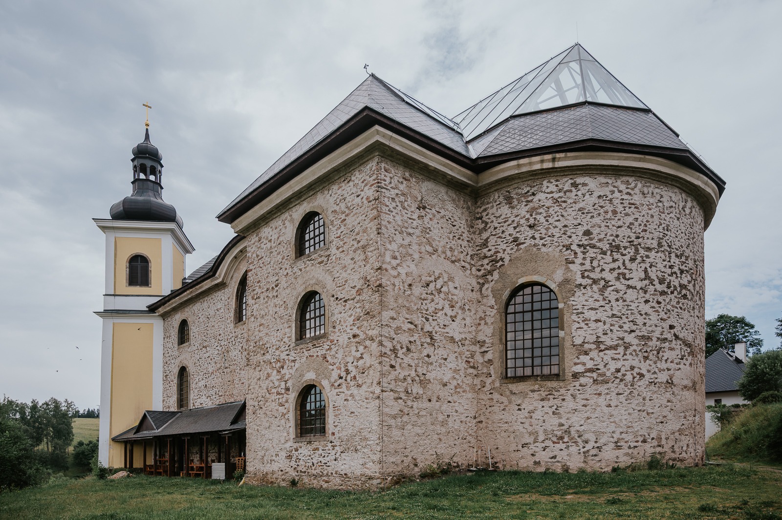 Skleněná střecha kostela v Neratově Kostel v Neratově zezadu se skleněnou střechou nad lodí a hrubým kamenným zdivem