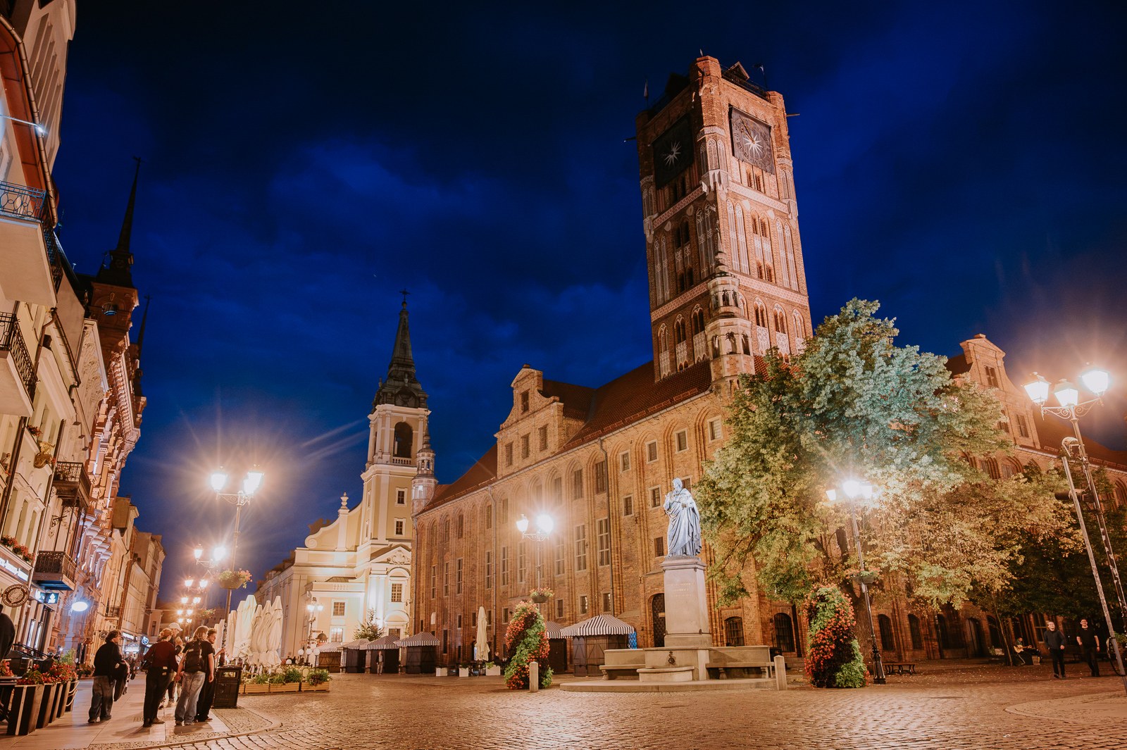 Rynek Staromiejski v Toruni večer Nasvícená gotická radnice na Rynku Staromiejském v Toruni večer s pomníkem Mikuláše Koperníka v popředí