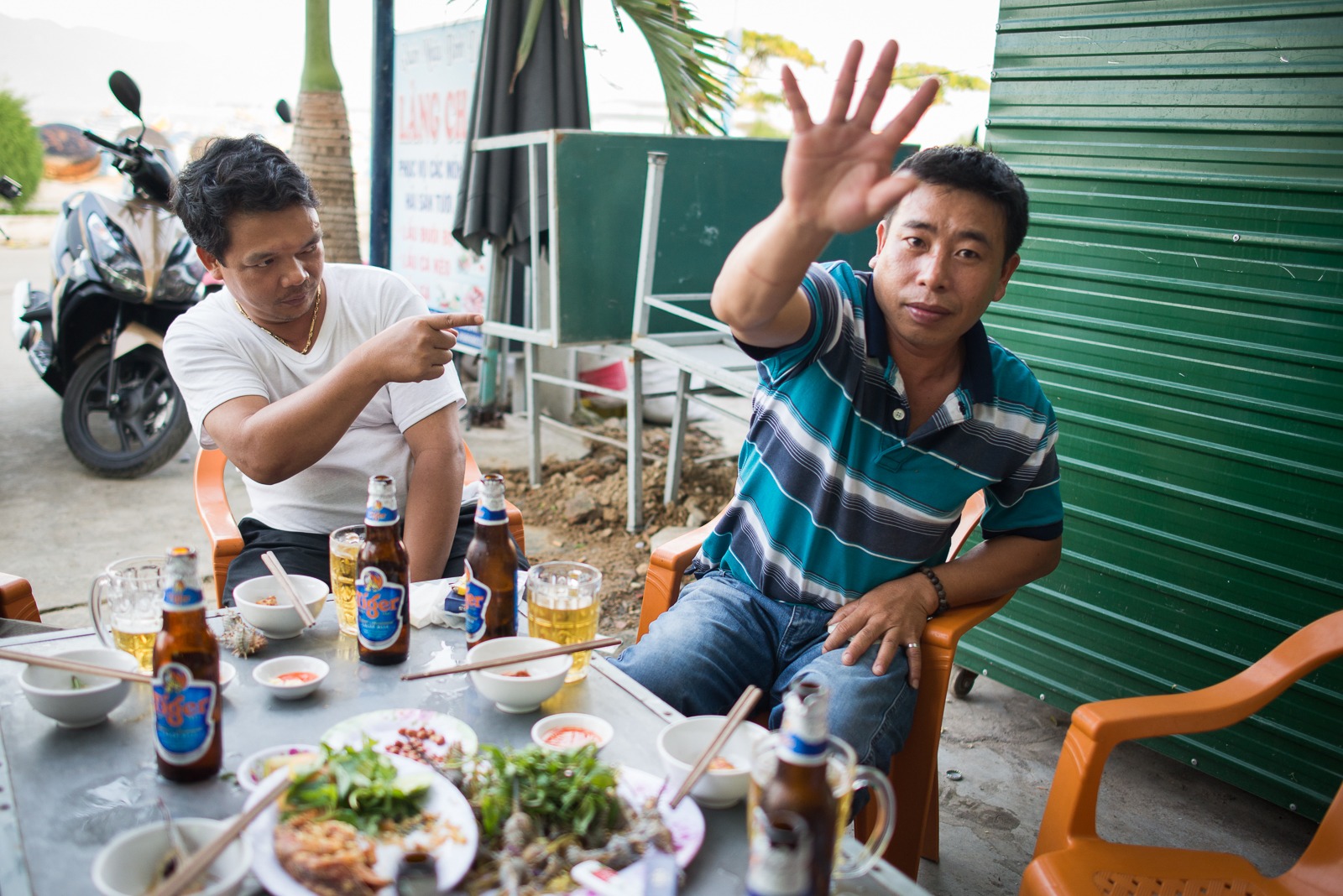 Vietnamští muži u stolu s mořskými plody a pivem Tiger v rybářské restauraci
