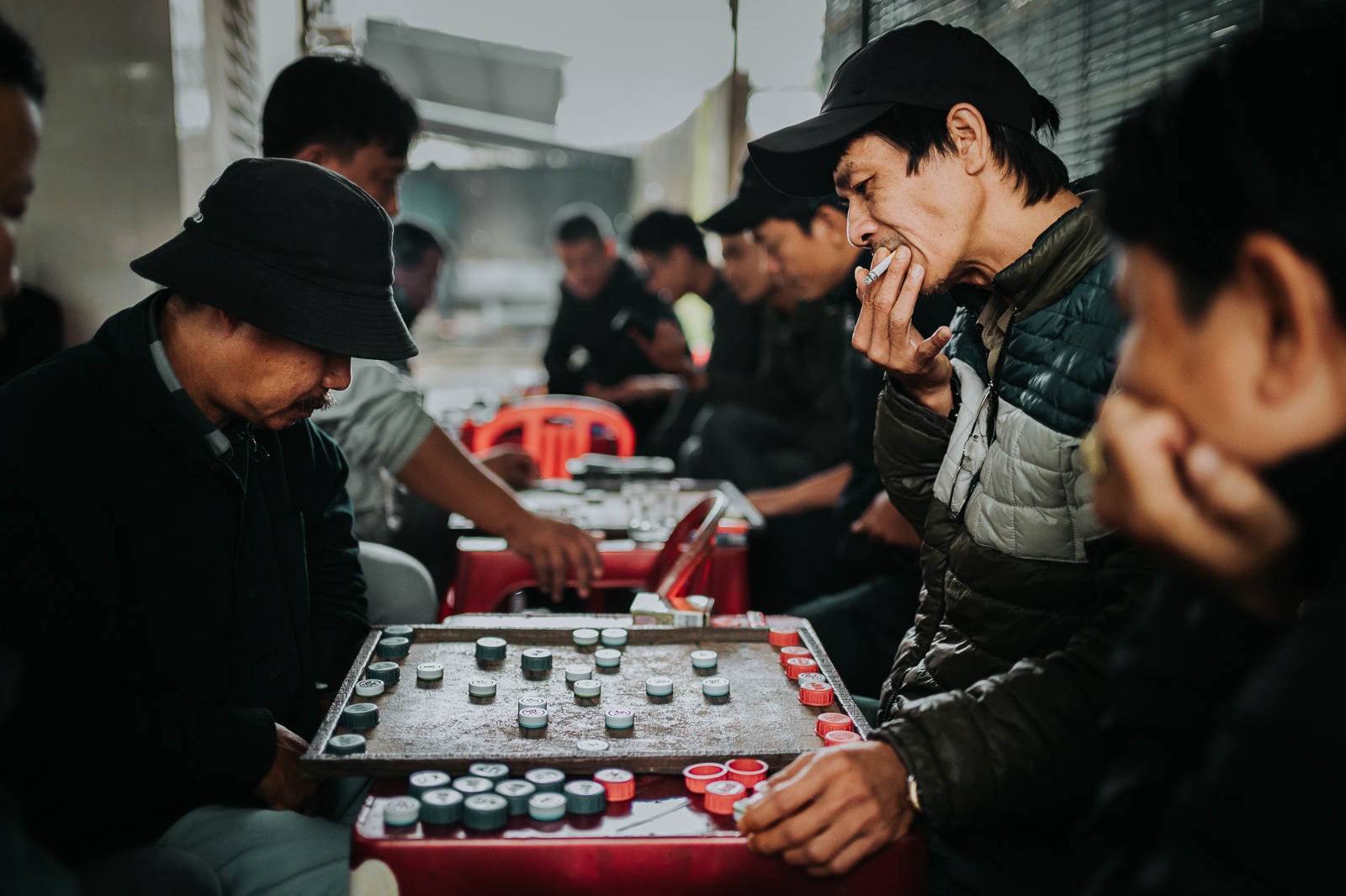 Vietnamští muži hrající šachy xiangqi s figurkami z lahvových víček