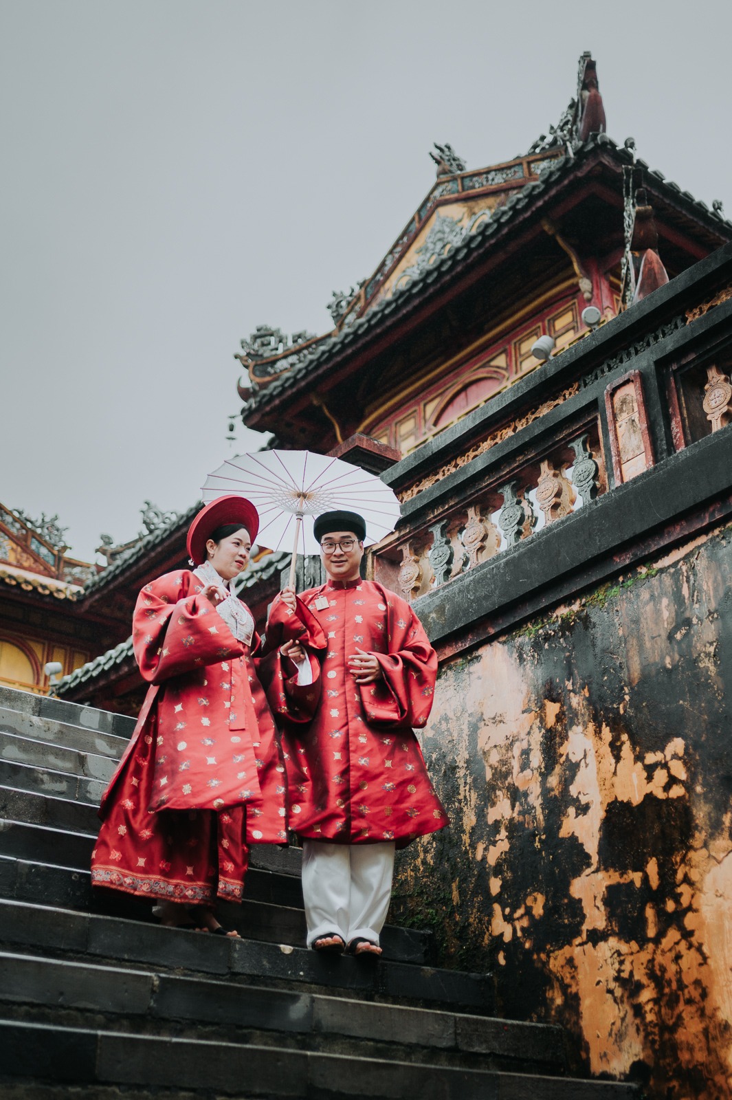 Vietnamský pár v tradičních rudých ao dai na schodech císařské citadely v Hue
