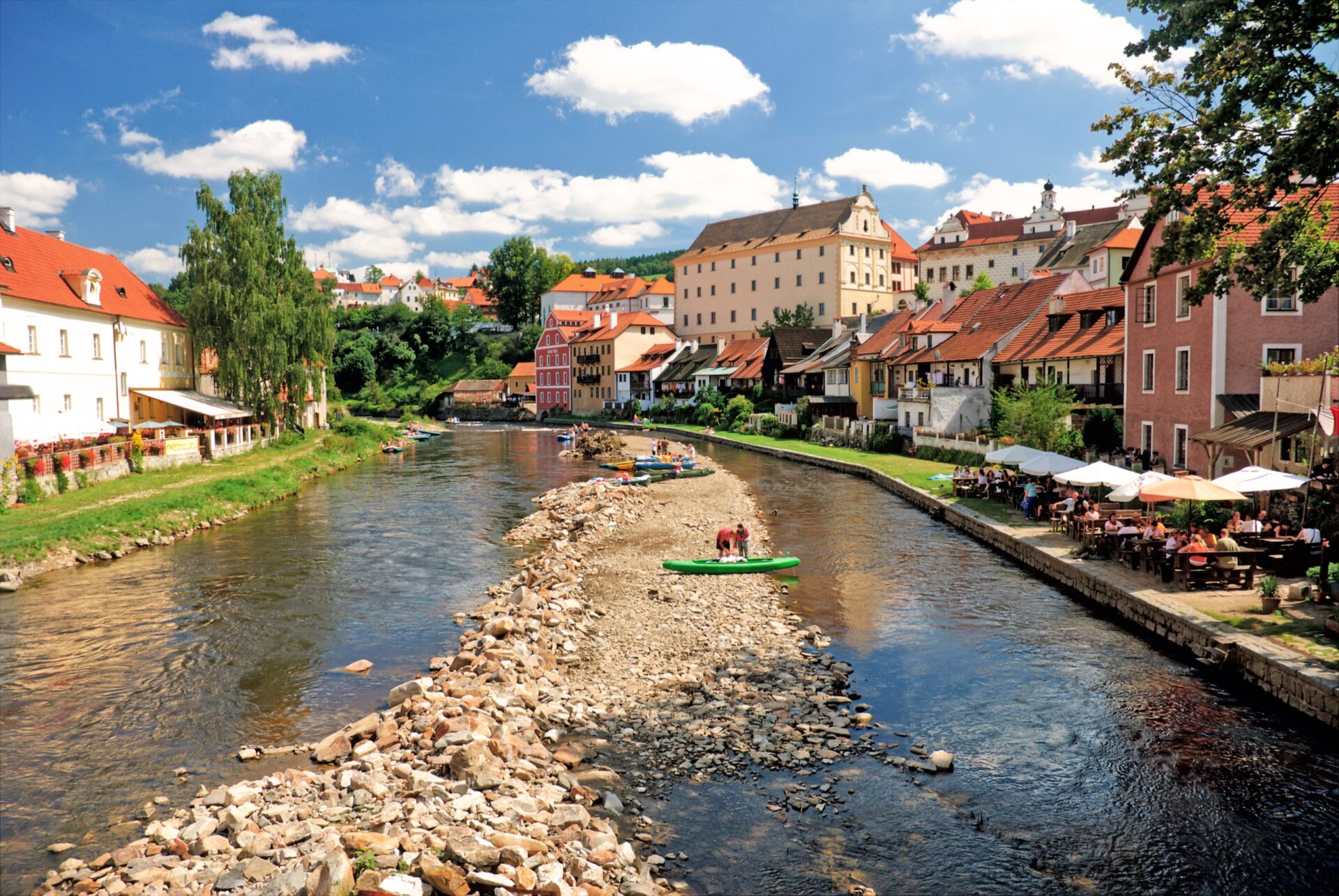 Vltava s loděmi a kamenitým břehem v Českém Krumlově