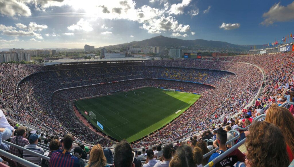 Zaplněné hlediště Camp Nou během zápasu FC Barcelona s pohledem na hřiště a vrch Tibidabo