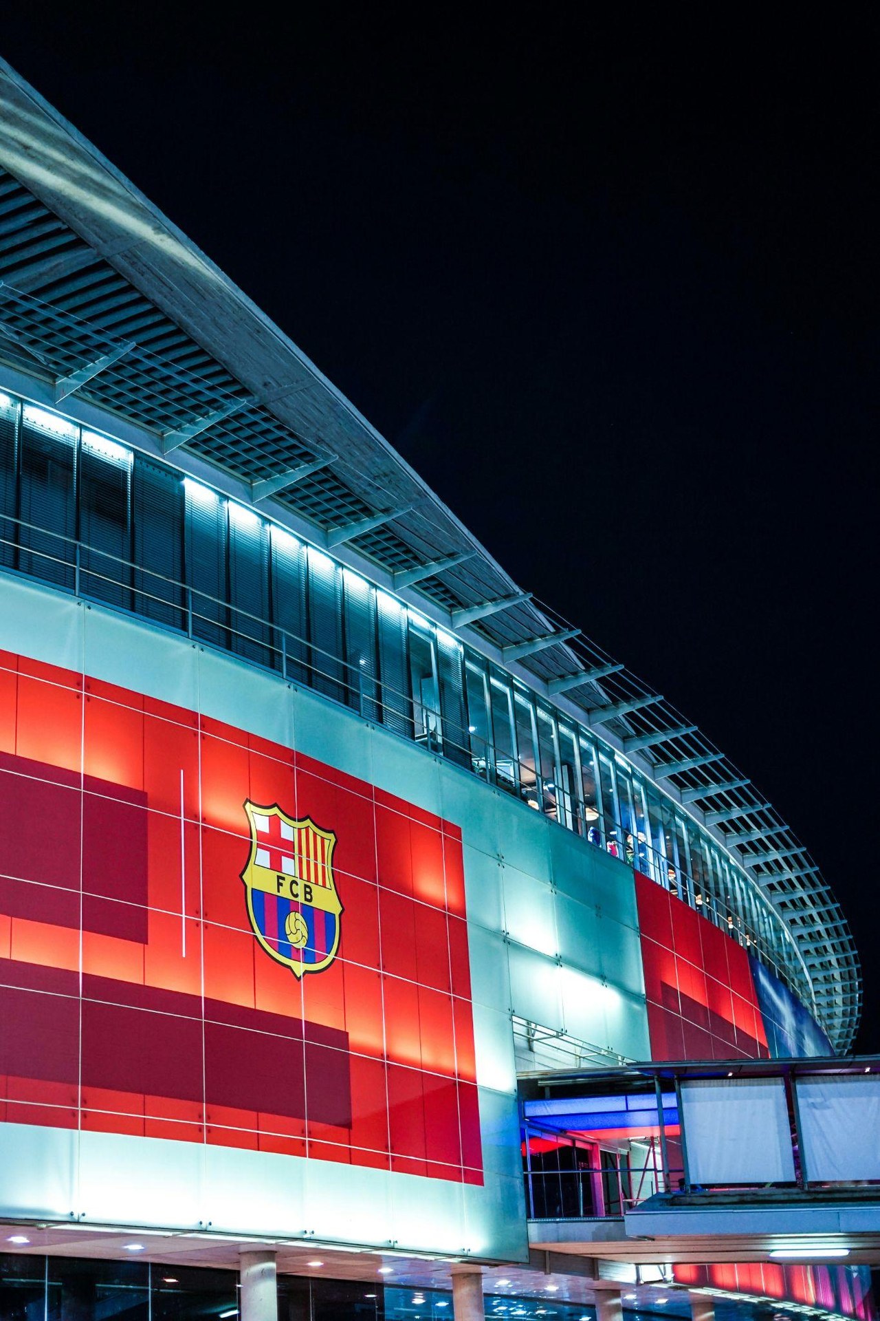 Nasvícená fasáda Camp Nou v noci s emblémem FC Barcelona