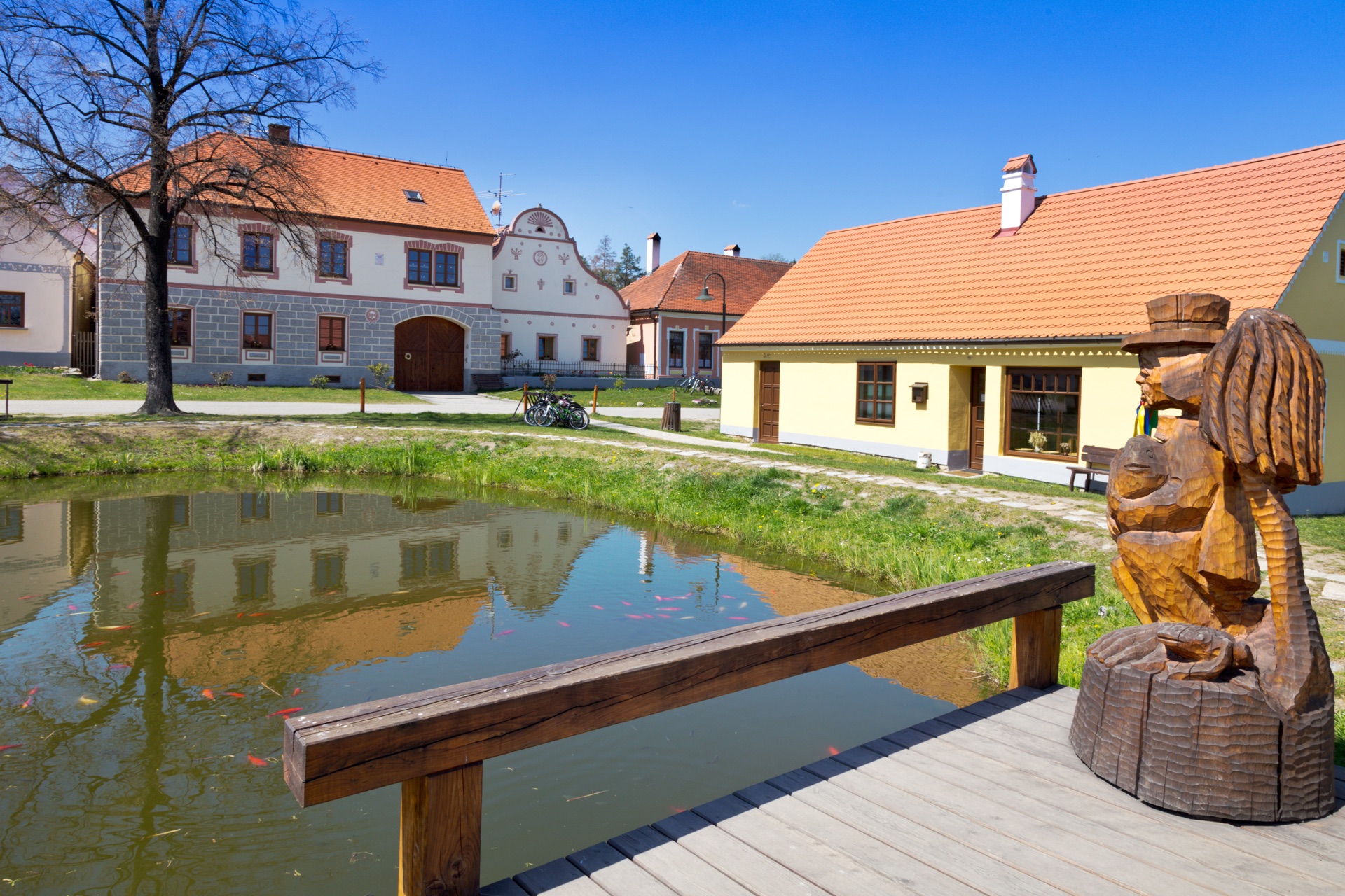 Molo s dřevěnou sochou vodníka u návesního rybníčku v Holašovicích