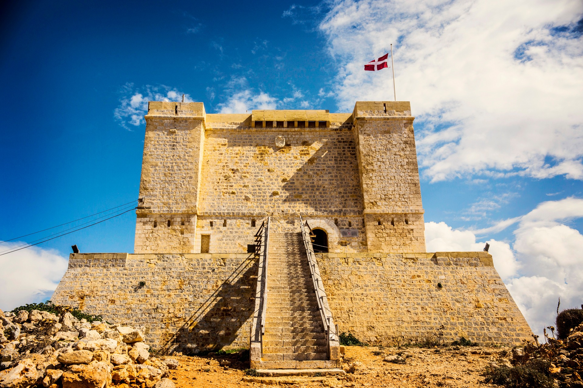 Věž Santa Marija Tower na ostrově Comino nad skalnatou krajinou
