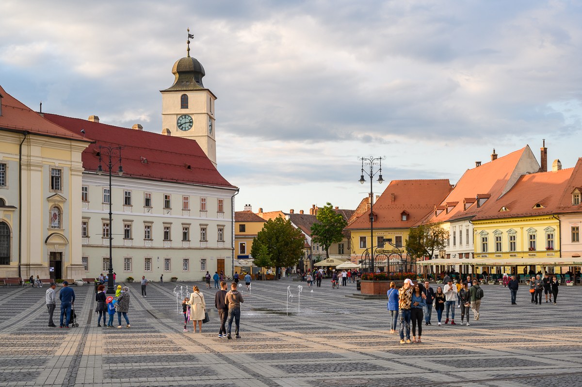 Velké náměstí v Sibiu s Radniční věží a lidmi za podvečerního světla