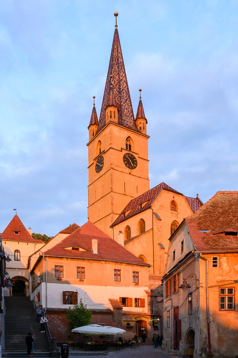 Evangelická katedrála v Sibiu s barevnou glazovanou střechou nasvícená západem slunce