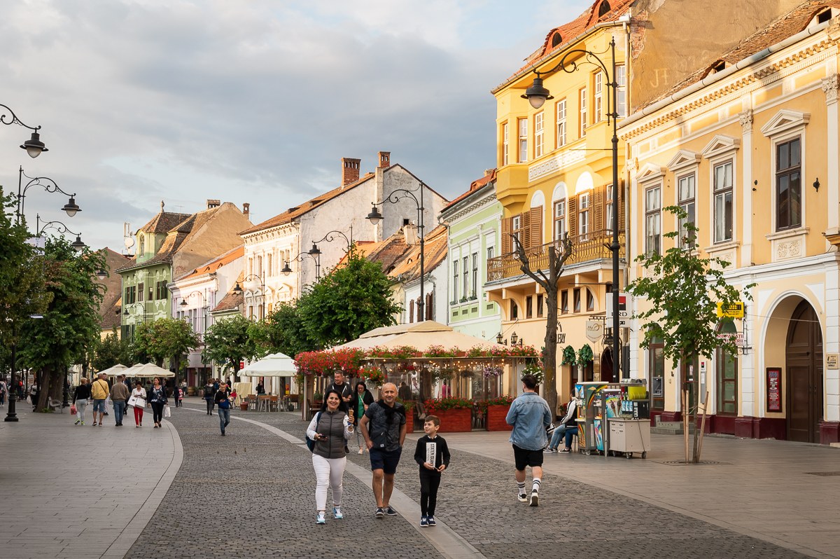Pěší zóna v centru Sibiu s barevnými měšťanskými domy a procházejícími lidmi