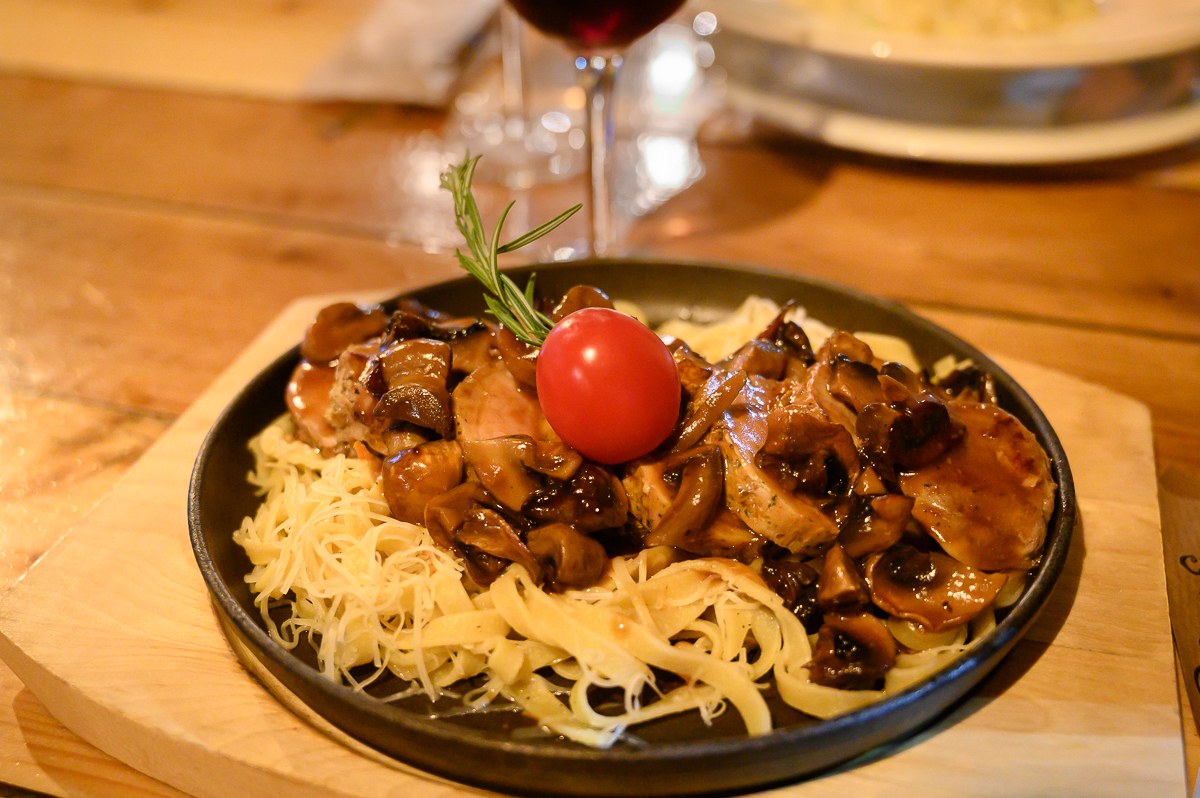 Talíř masa s houbovou omáčkou a sklenkou rumunského vína v restauraci