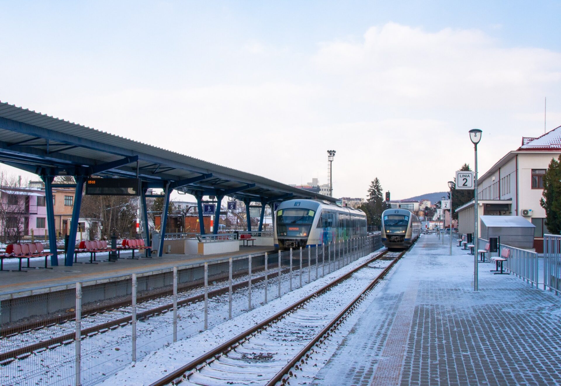 Regionální vlaky CFR na zasněženém nástupišti rumunského nádraží