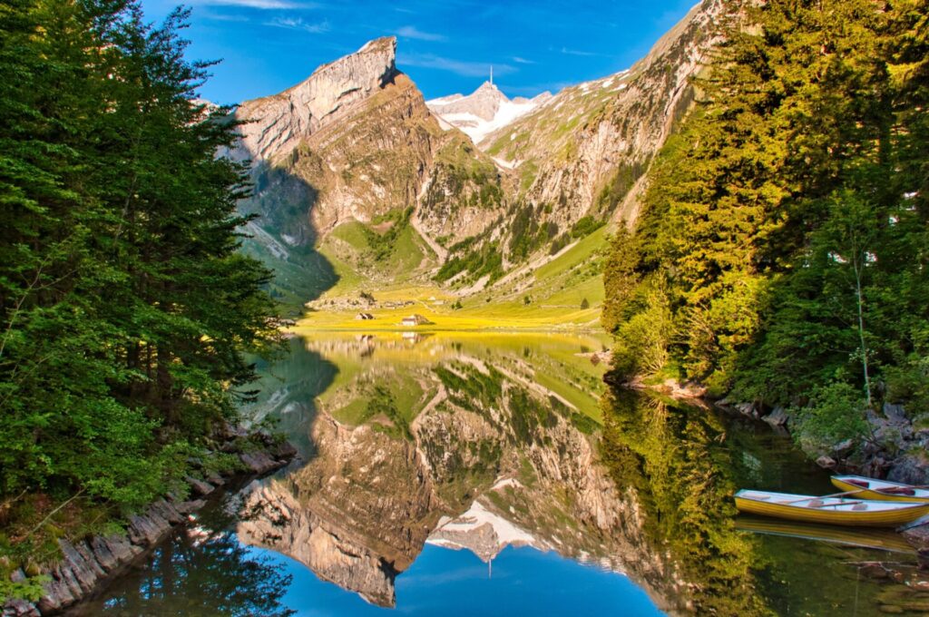 Seealpsee Jezero Seealpsee v Appenzellu s odrazem masivu Säntis a dřevěnými loďkami