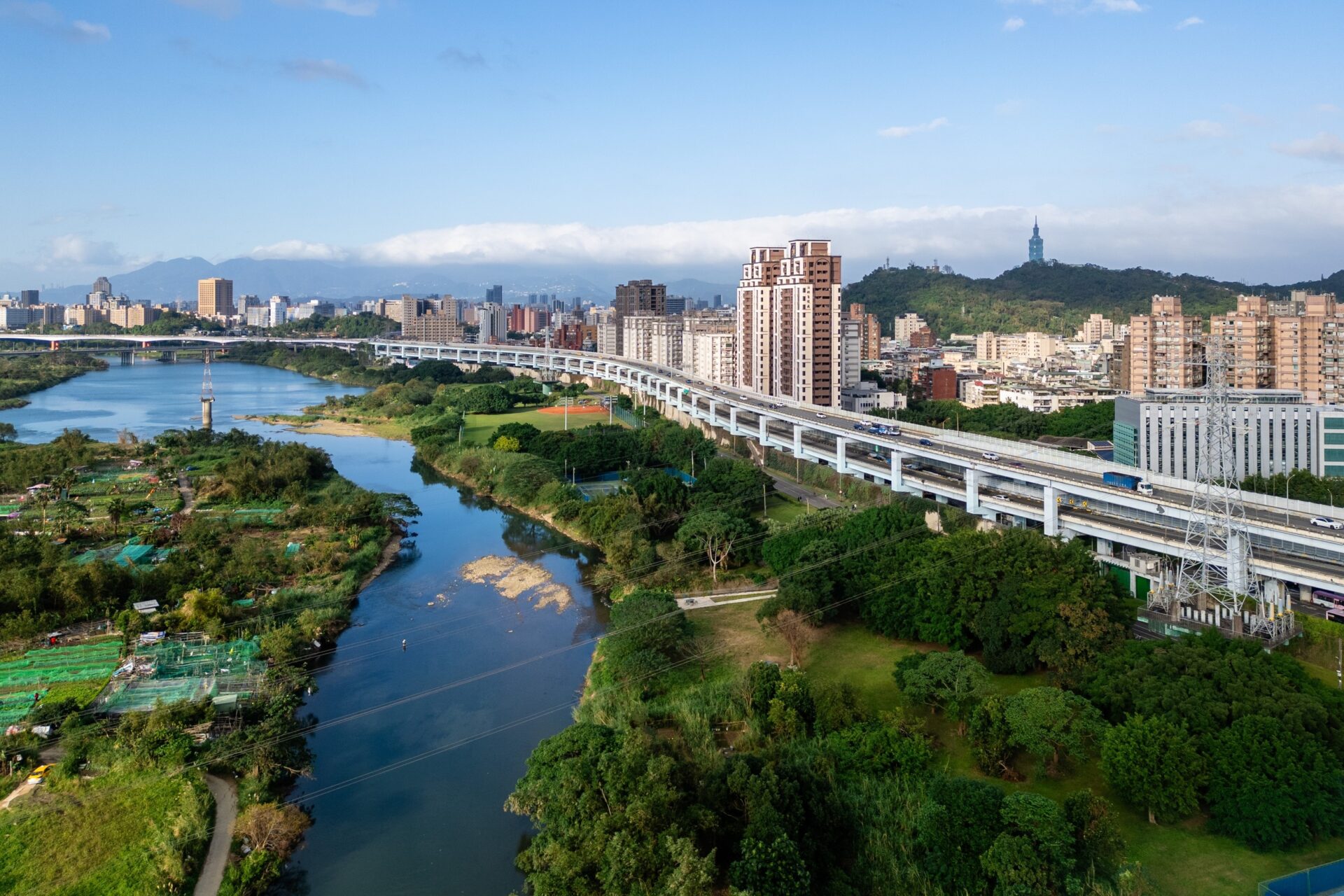 Nábřeží řeky v Taipei s mostem, zelení a městskou dopravou