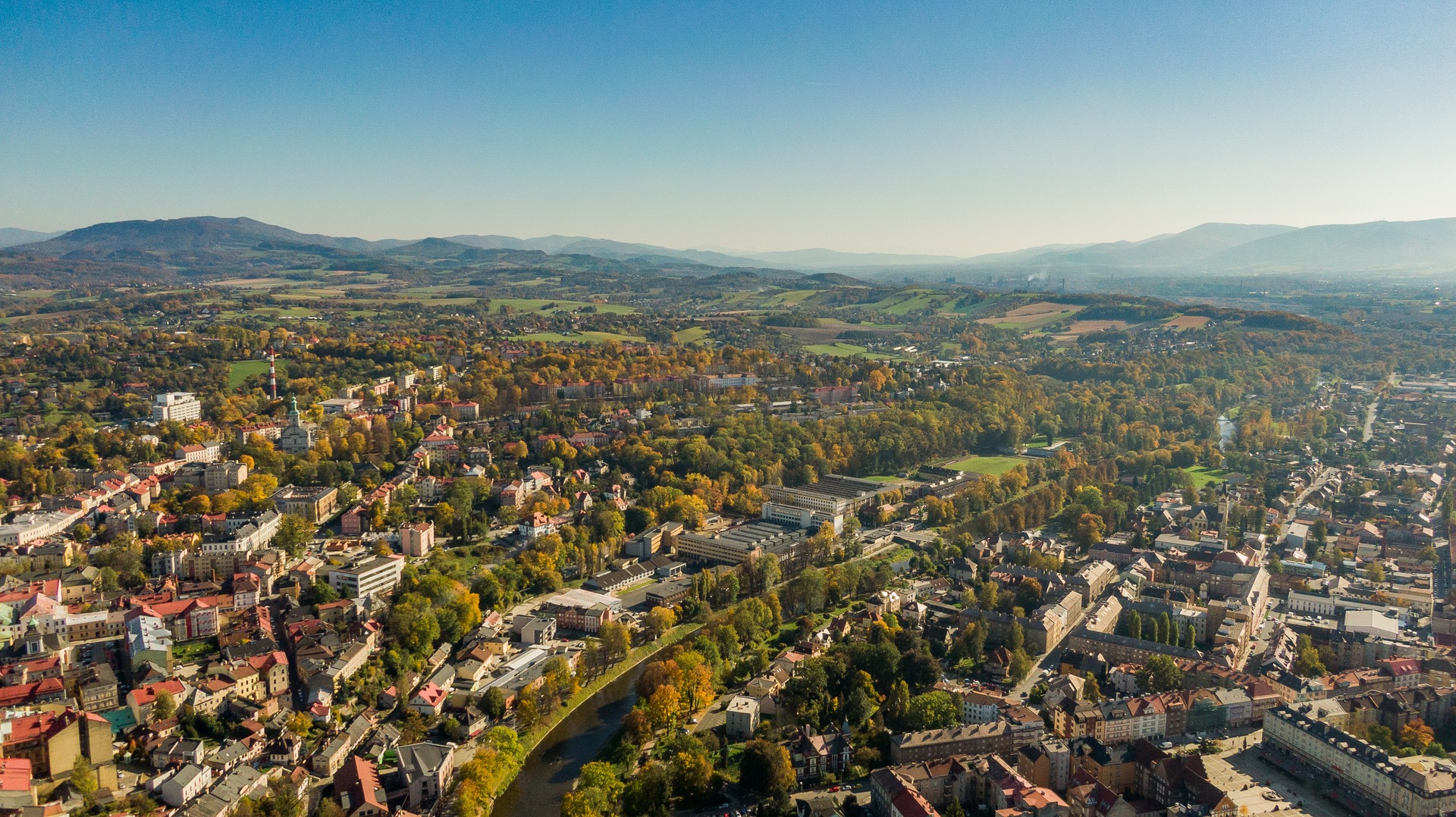 Letecký pohled na dvojměstí Cieszyn a Český Těšín rozdělené řekou Olší, v pozadí Slezské Beskydy