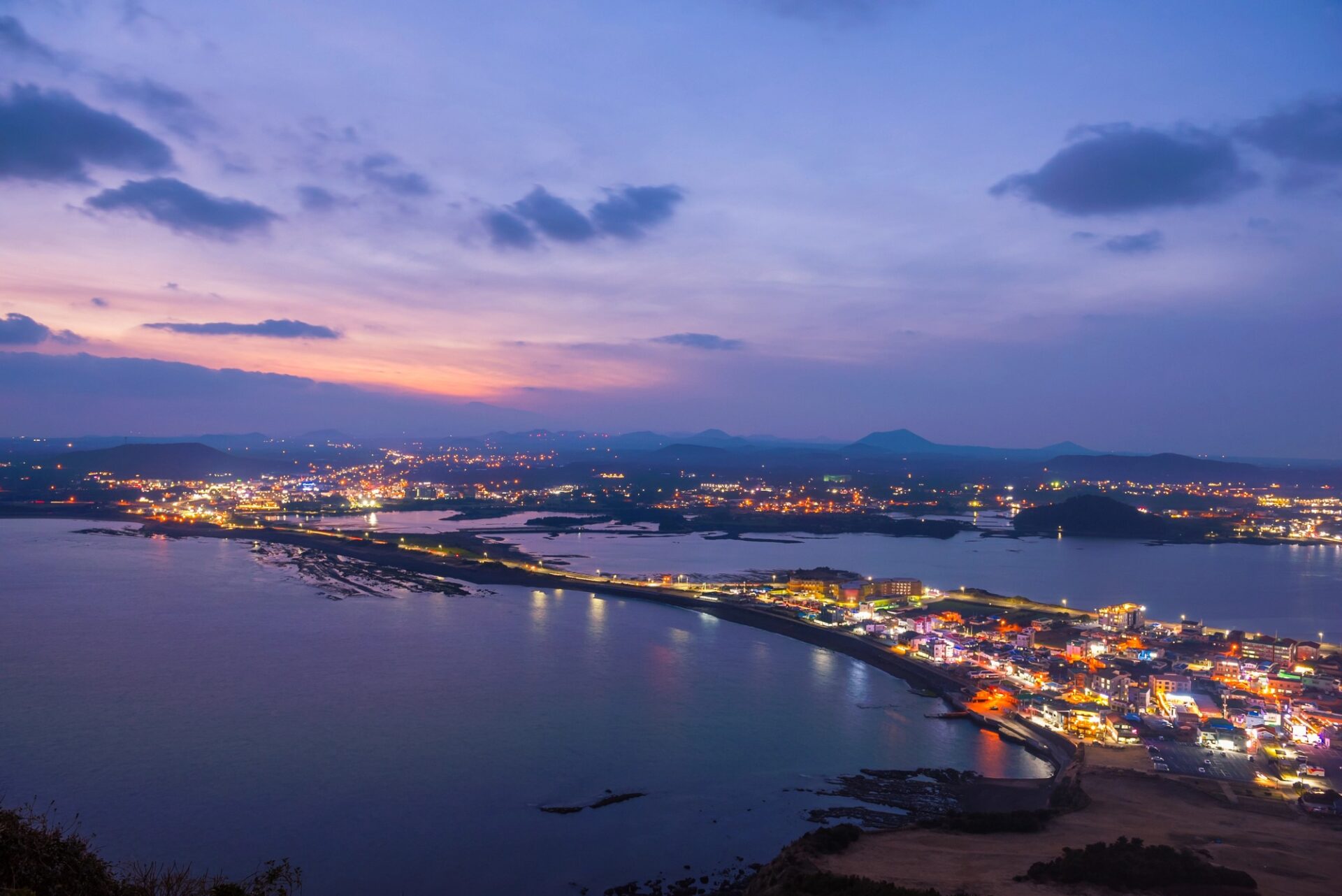 Večerní pohled na Seongsan Ilchulbong a světla pobřeží ostrova Jeju