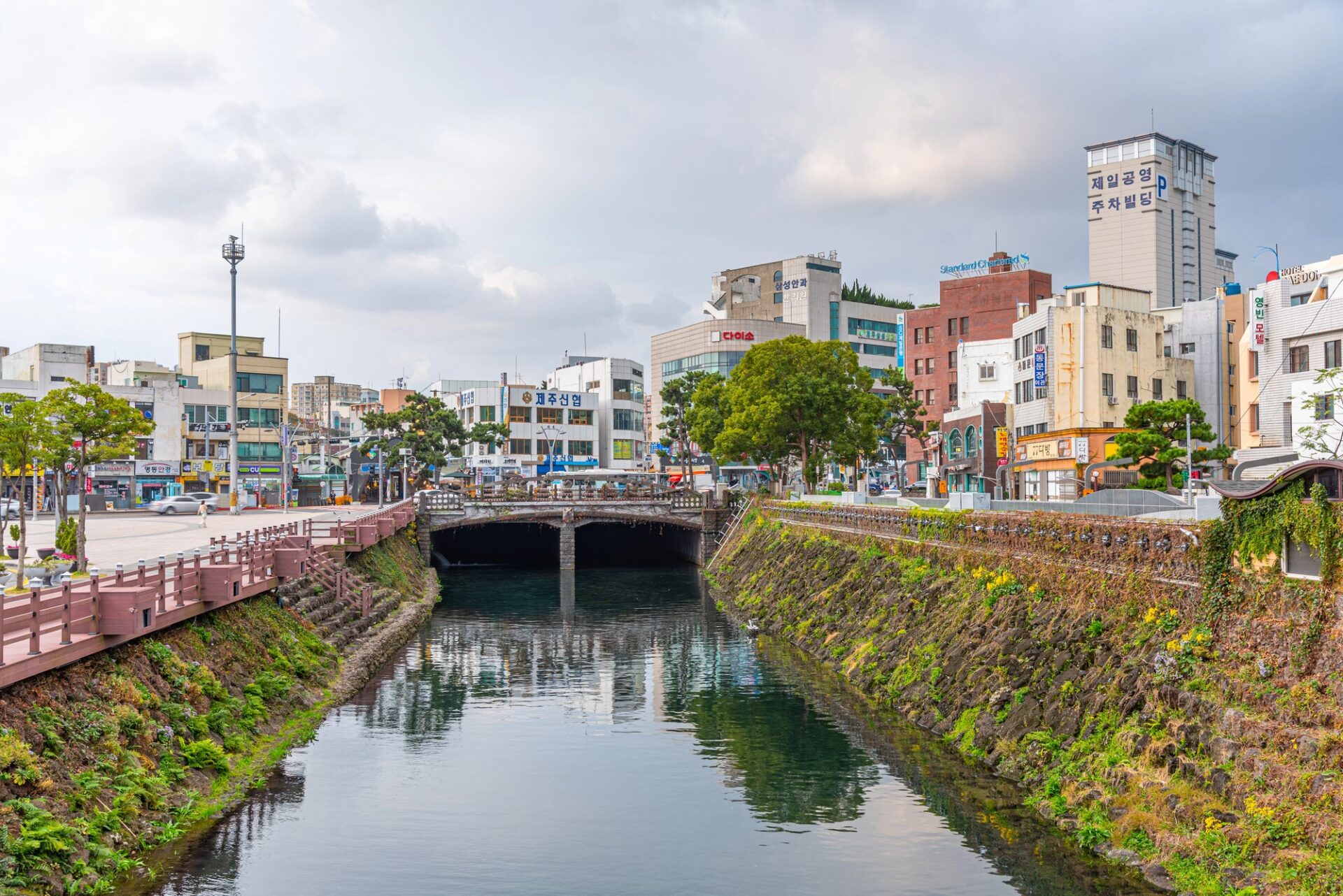 Kanál v centru Jeju City s nízkou zástavbou a mosty