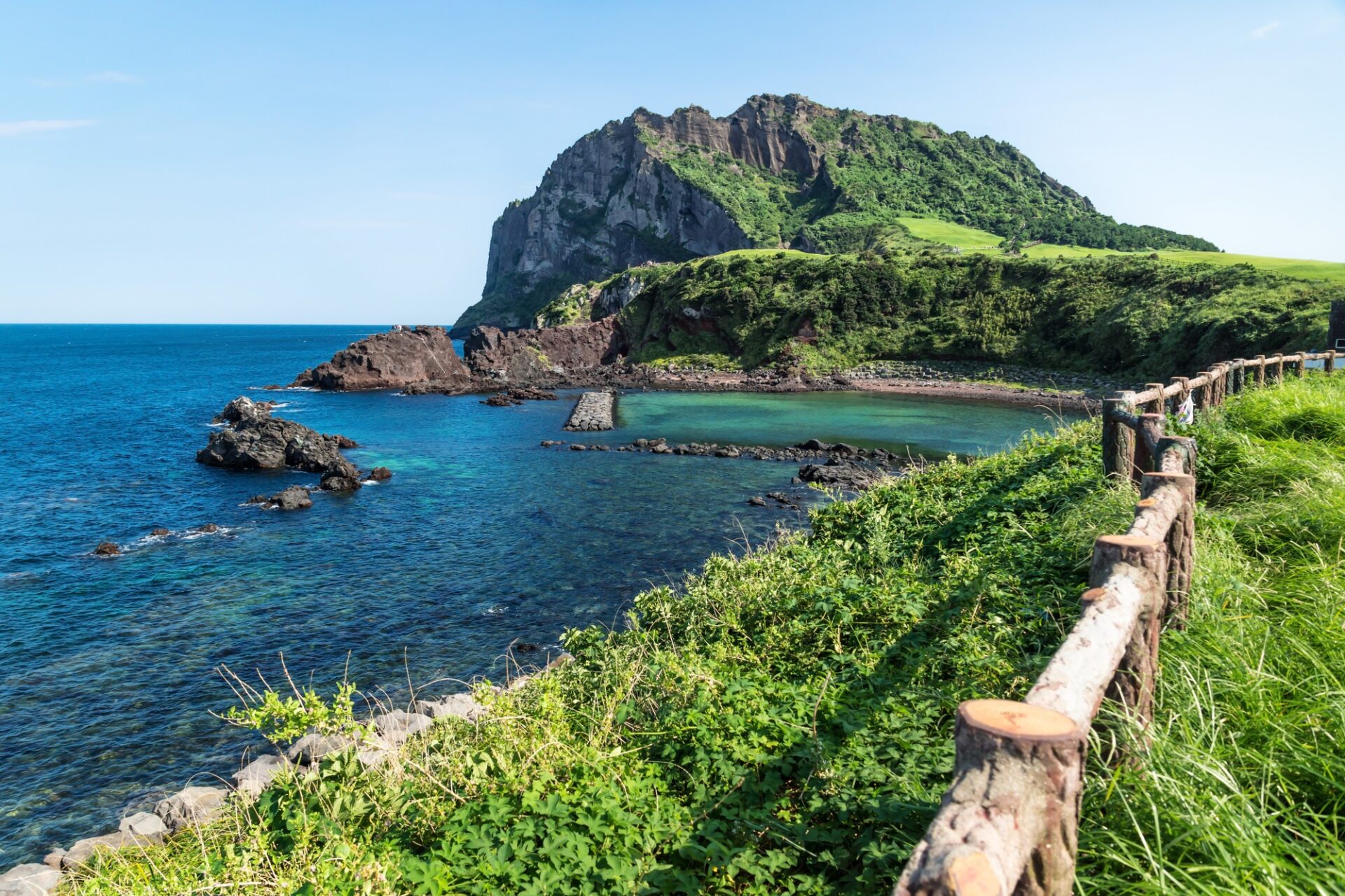 Pláž a zelené pobřeží pod Seongsan Ilchulbong na ostrově Jeju