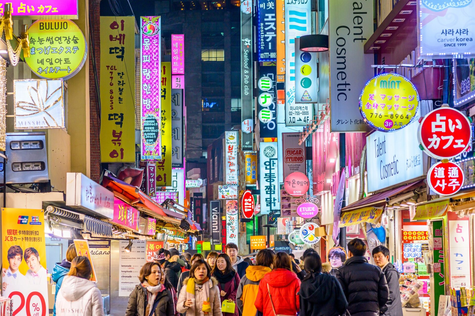 Noční ulice Myeongdong v Soulu plná neonů, obchodů a lidí