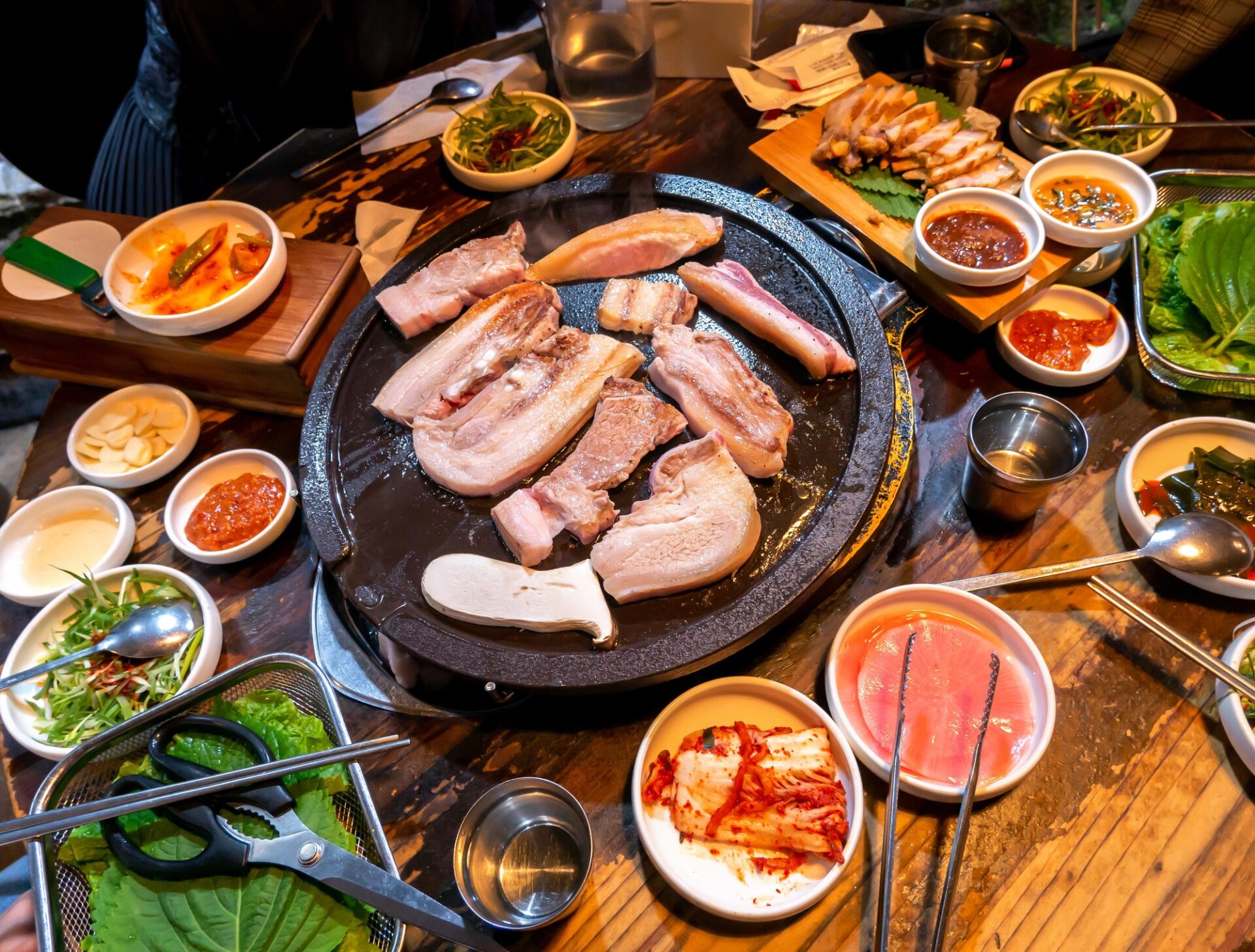 Korejské barbecue s masem na grilu, kimchi a malými přílohami banchan