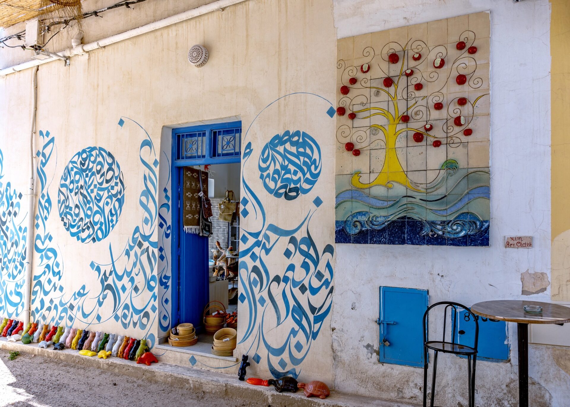 Street art v Djerbahoodu Barevný street art na bílé fasádě v djerbské vesnici Djerbahood