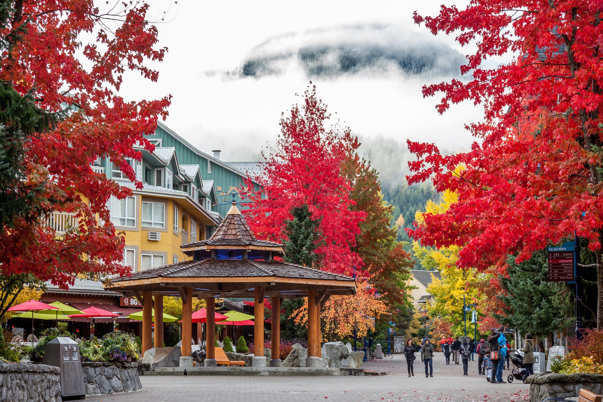 Pěší ulice ve Whistler Village mezi stromy s červeným podzimním listím