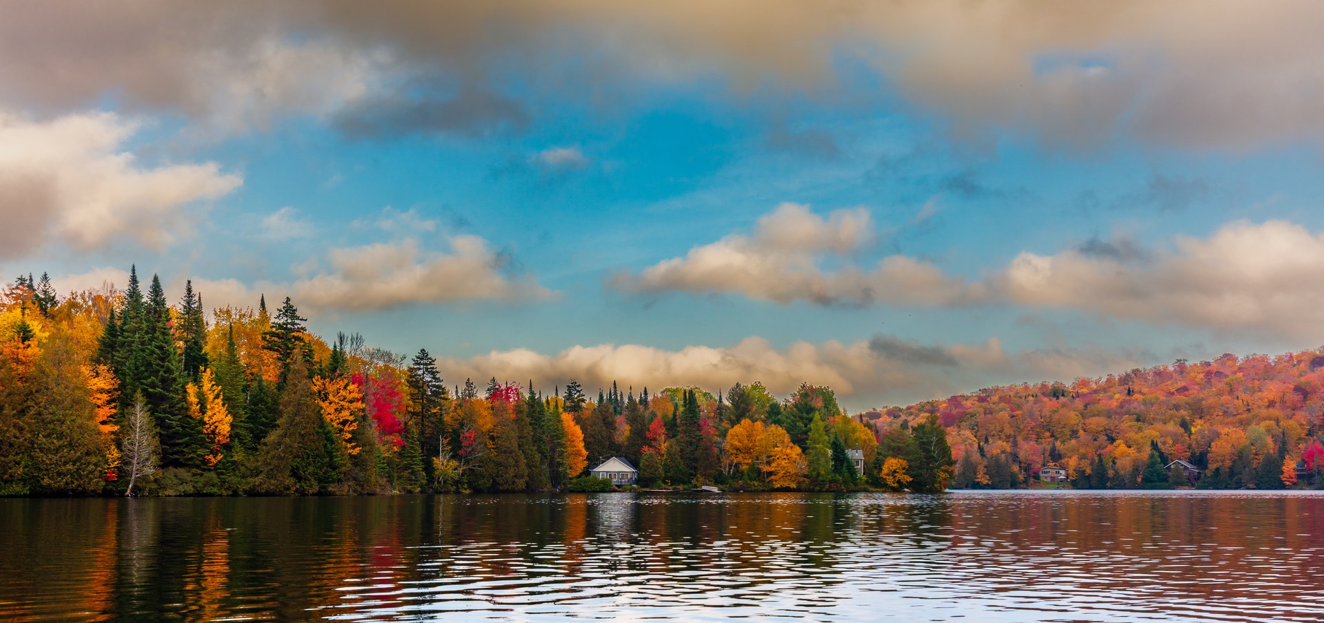 Jezero obklopené žlutými a červenými podzimními lesy v Laurentides v Québecu